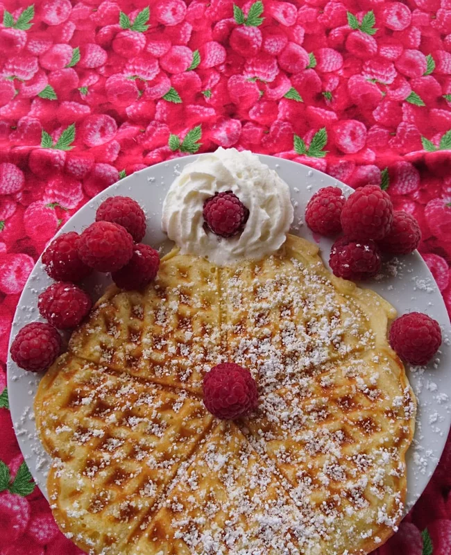 Selbstgebackene Waffel mit Sahne, Himbeeren und Puderzucker