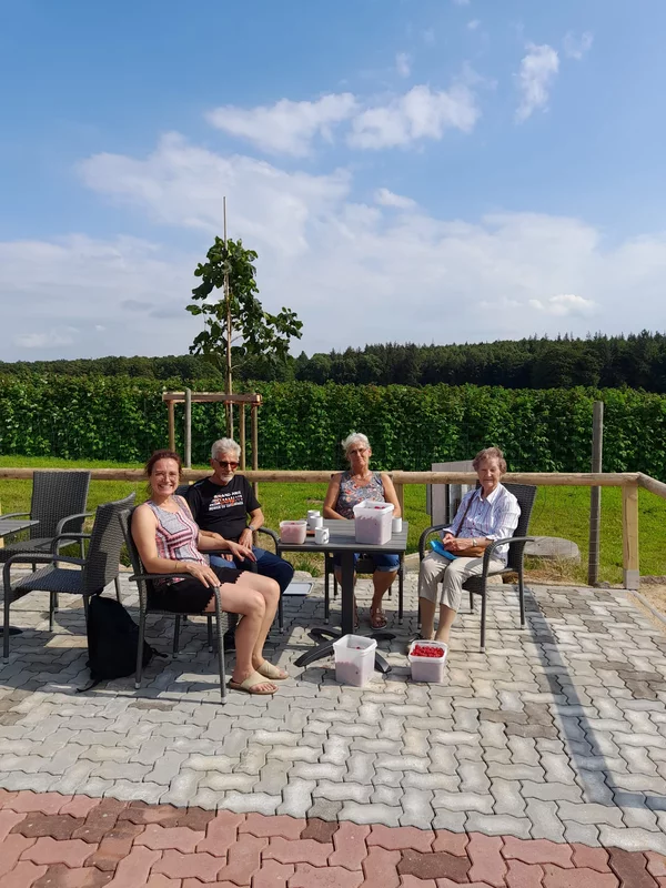 Besucher*innen auf der Terrasse mit gepflückten Himbeeren