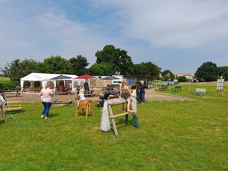 Spielbereich mit Holzreitpferden und Sandkiste Holzreitpferde und eine Sandkiste mit spielenden Kindern