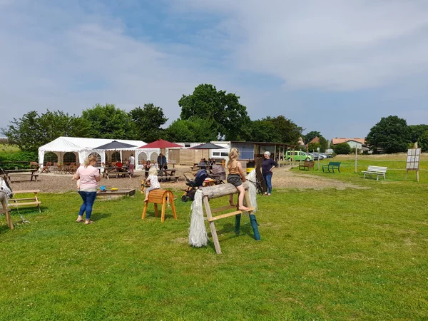 Holzreitpferde und eine Sandkiste mit spielenden Kindern