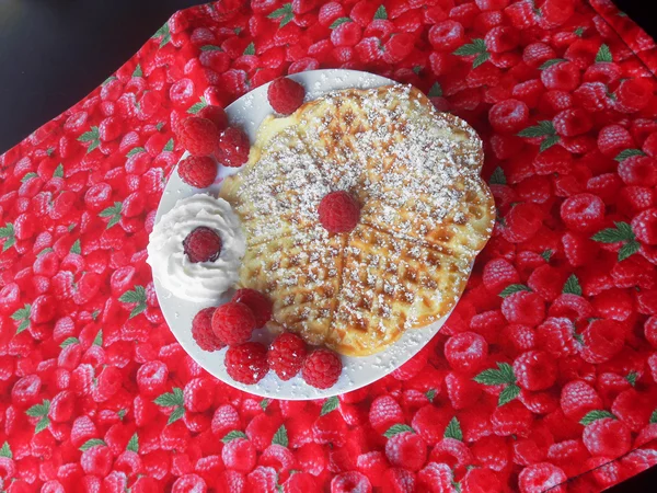 Selbstgebackene Waffel mit Himbeeren, Sahne und Puderzucker